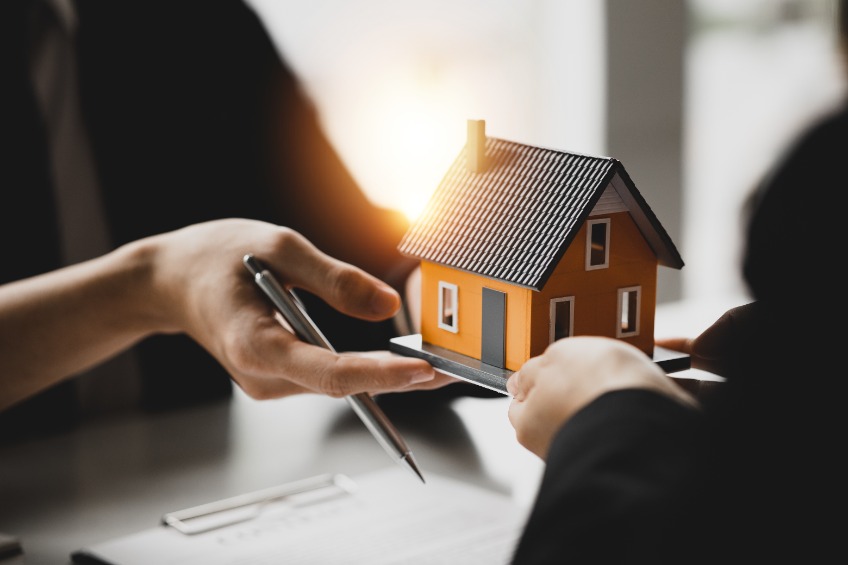 A person hands over a tiny house to another person.